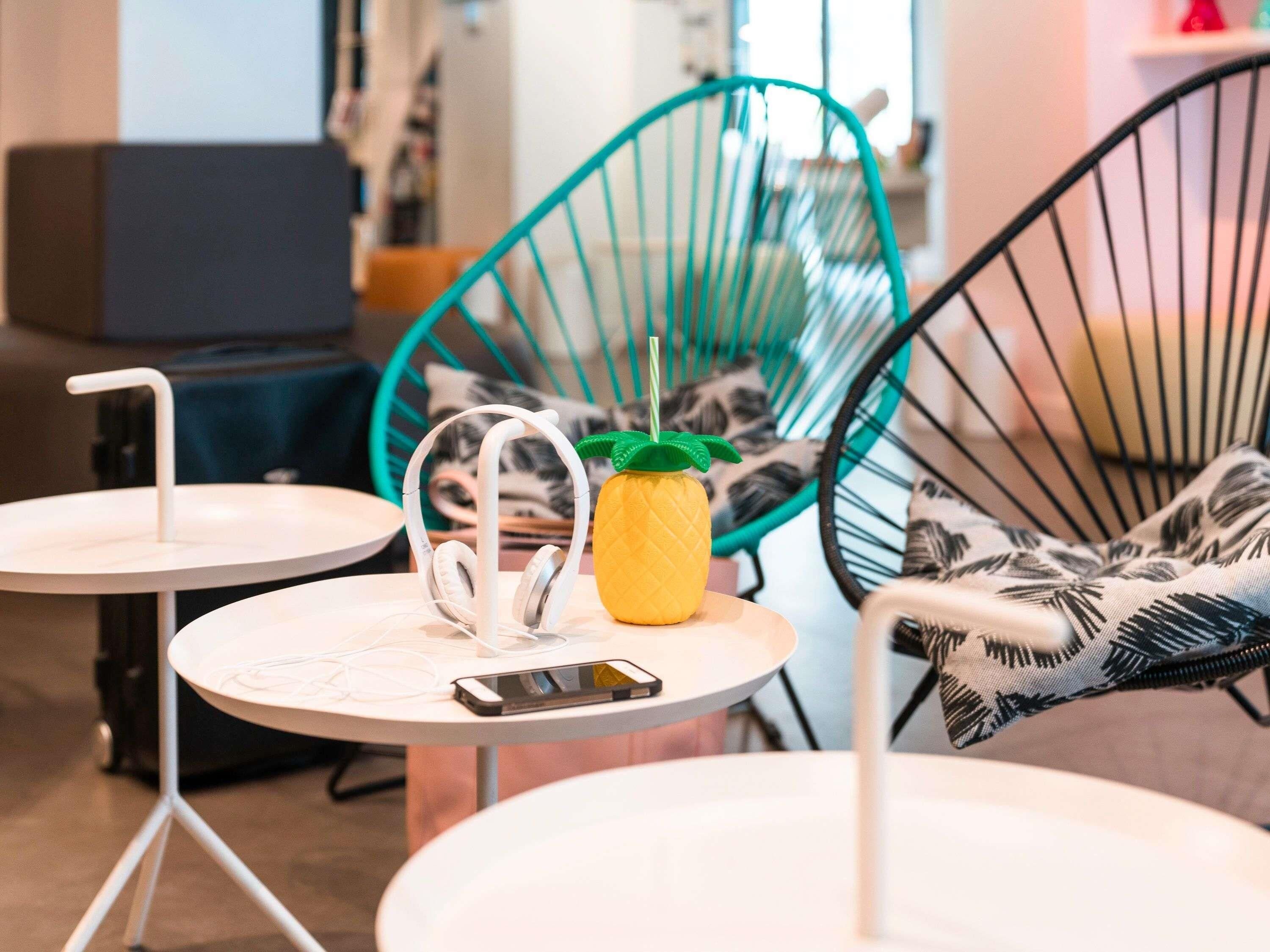 Un espace détente avec deux chaises, une petite table sur laquelle se trouve un téléphone intelligent et un porte-verres en forme d’ananas.