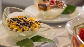 Two bowls of dessert on white plates with a green leaf garnish.
