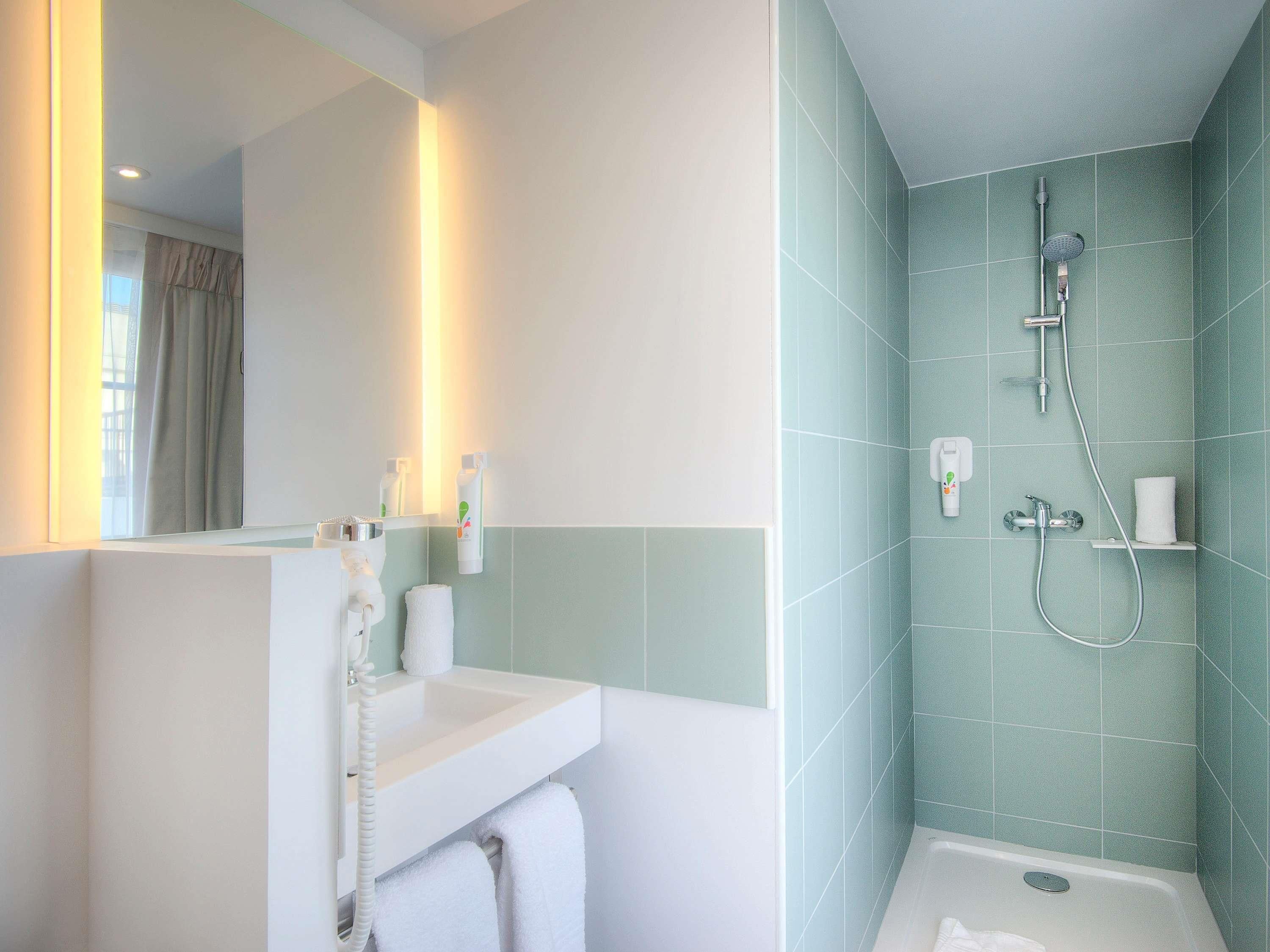 A bathroom with a sink, mirror, and shower.