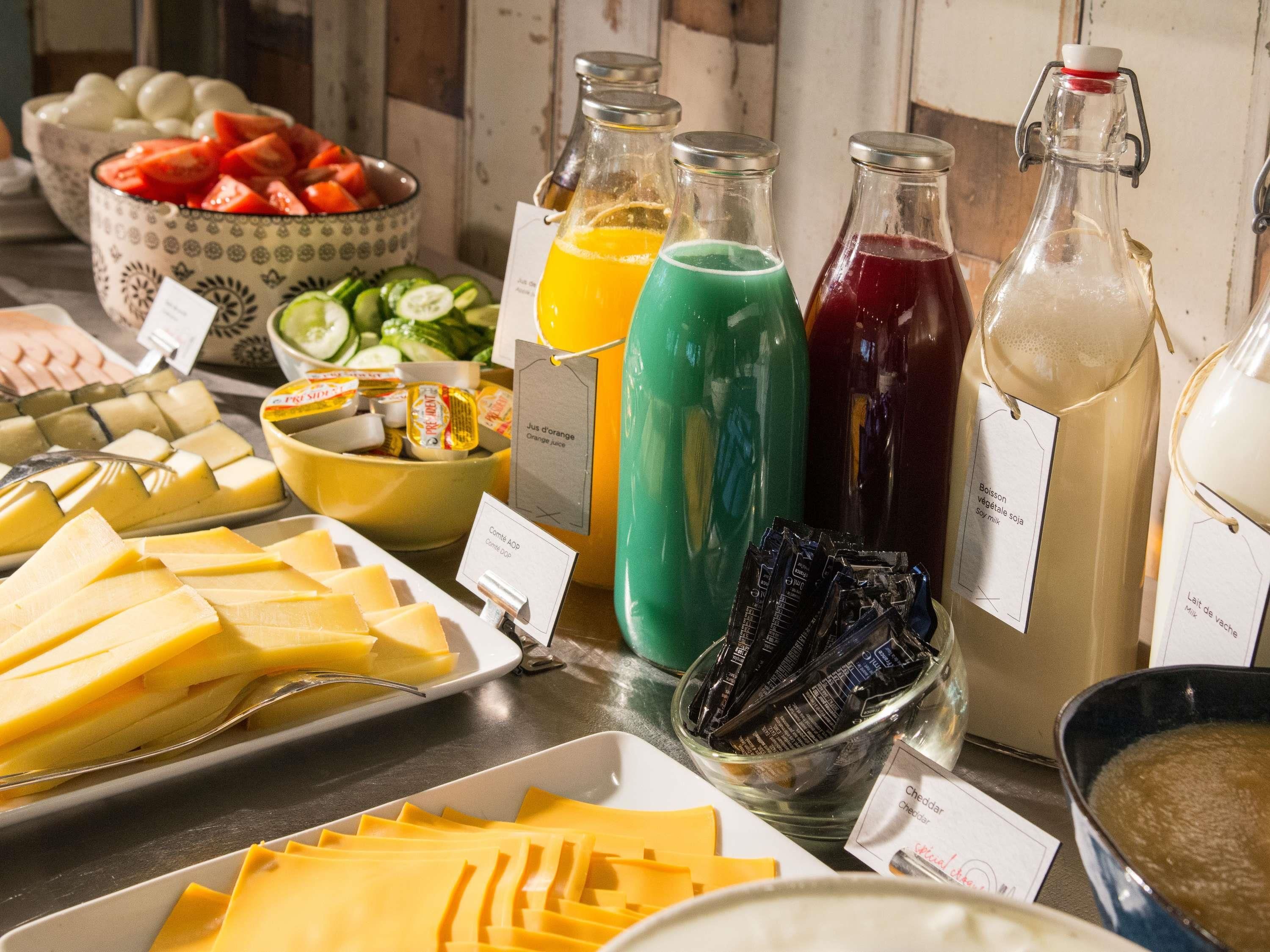 A buffet with various food items including cheese, fruits, and beverages.