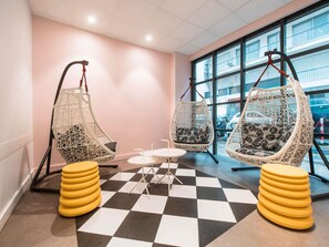 A room with two hanging chairs, a small table, and a checkered floor.