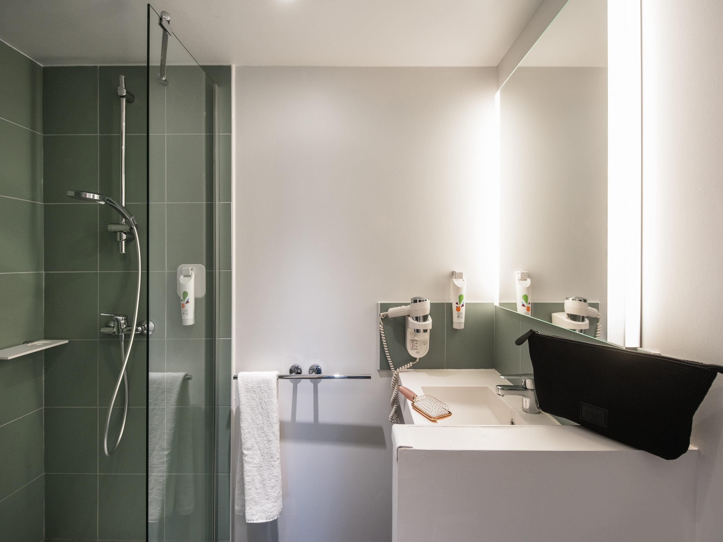 Un baño moderno con ducha de vidrio, lavamanos blanco y espejo.