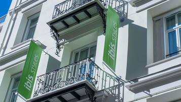 A building with a balcony featuring ornate black metal railings and a green banner with the text 'ibis styles'.