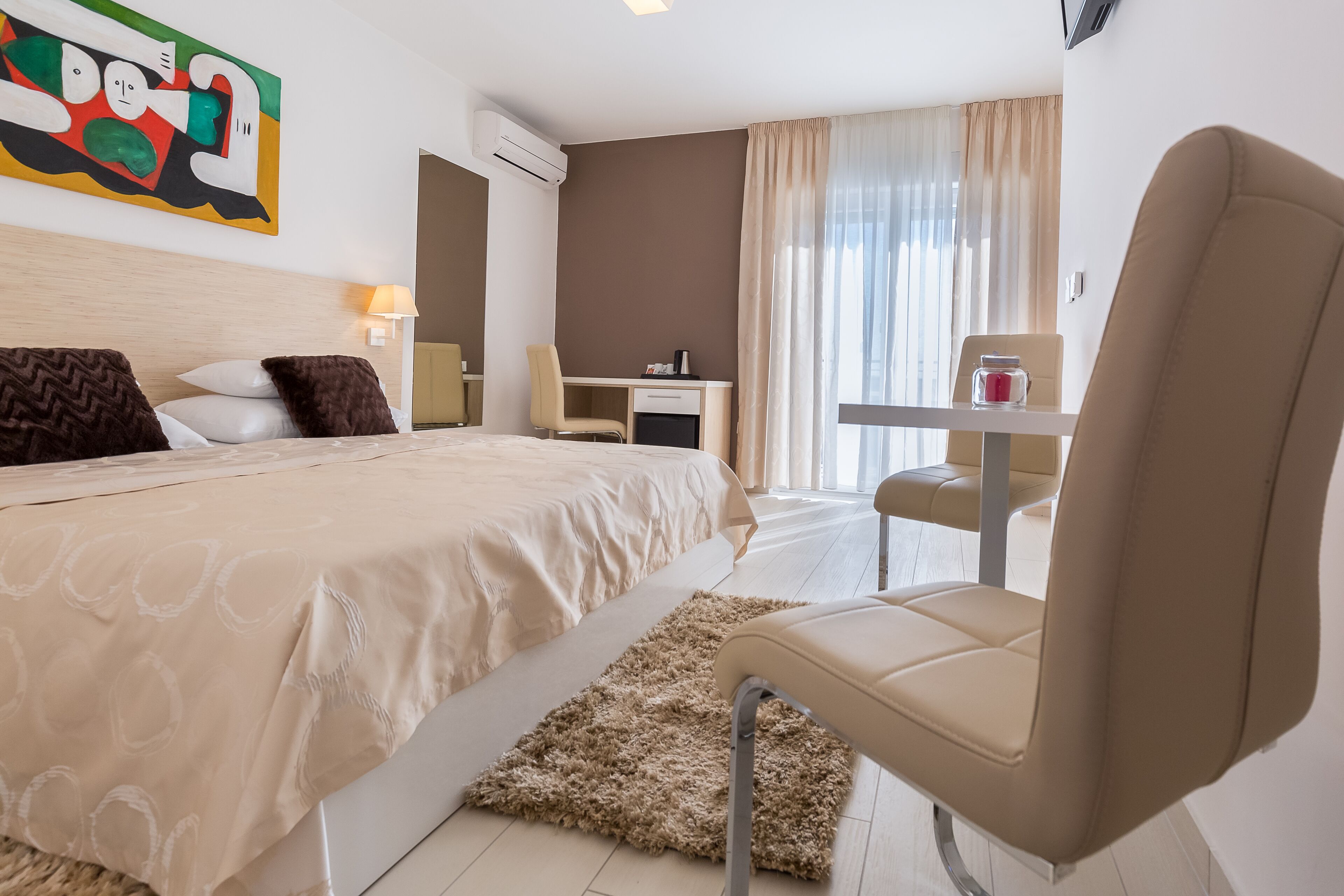 Habitació d'hotel amb llit, escriptori, cadira i una taula petita amb una espelma.