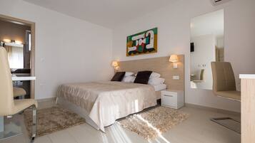 Une chambre d’hôtel moderne, équipée d’un lit, de tables de chevet, d’une chaise, d’un miroir et d’un tableau au mur.