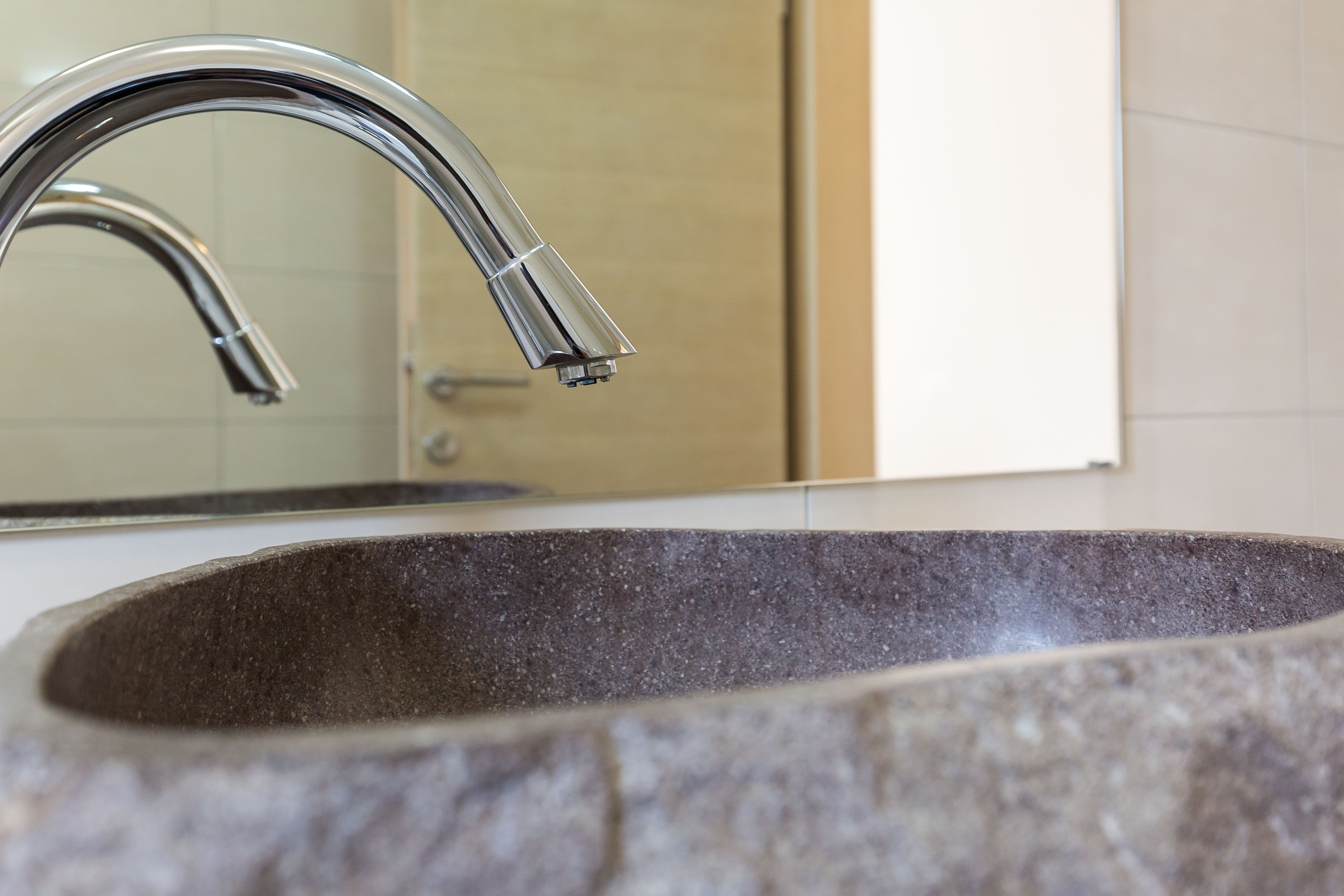 Un lavabo de salle de bain doté d’un robinet moderne et d’un plan de travail en granit.