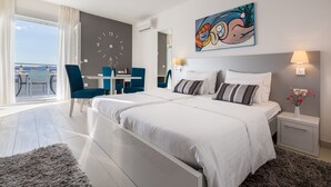 Et moderne hotelværelse med en stor seng, et skrivebord og havudsigt.