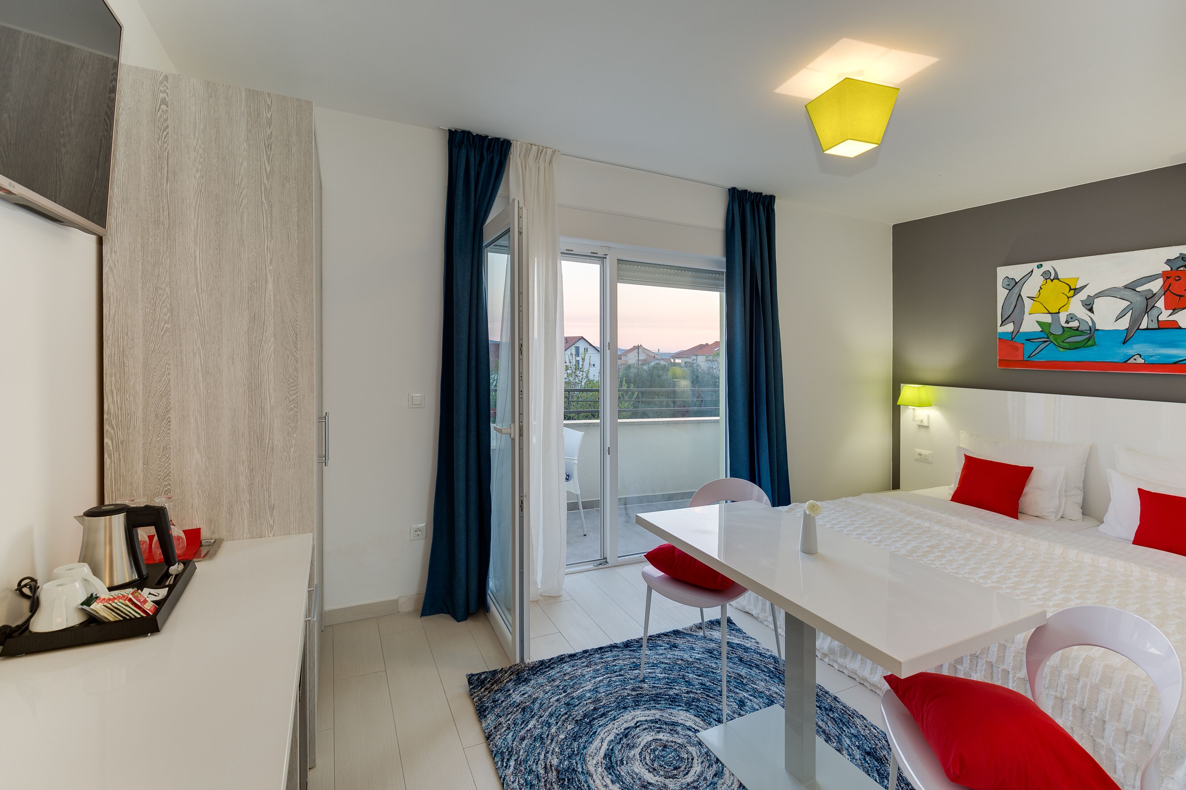 Une chambre d’hôtel équipée d’un lit, d’une table, d’une chaise, d’une machine à café et offrant une vue sur l’extérieur.