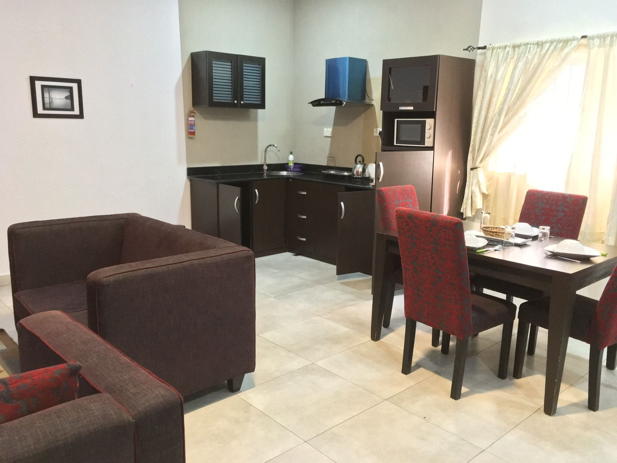 A compact kitchen with a dining area, including a sofa and chairs.