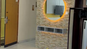 A dining area with a stone wall, a round mirror, and a dining table with chairs.