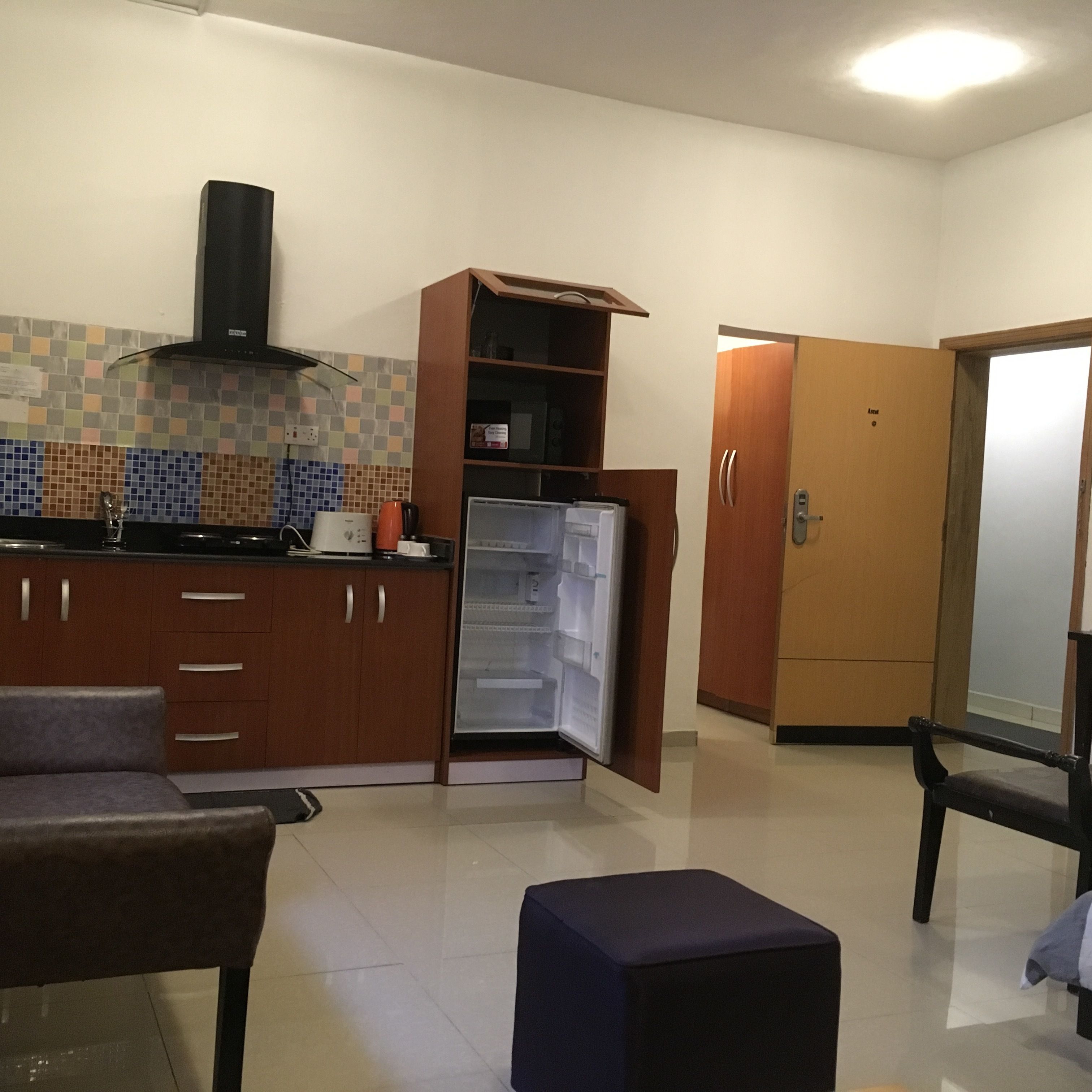 Una cucina compatta con frigorifero, mobili in legno e rivestimento a mosaico.