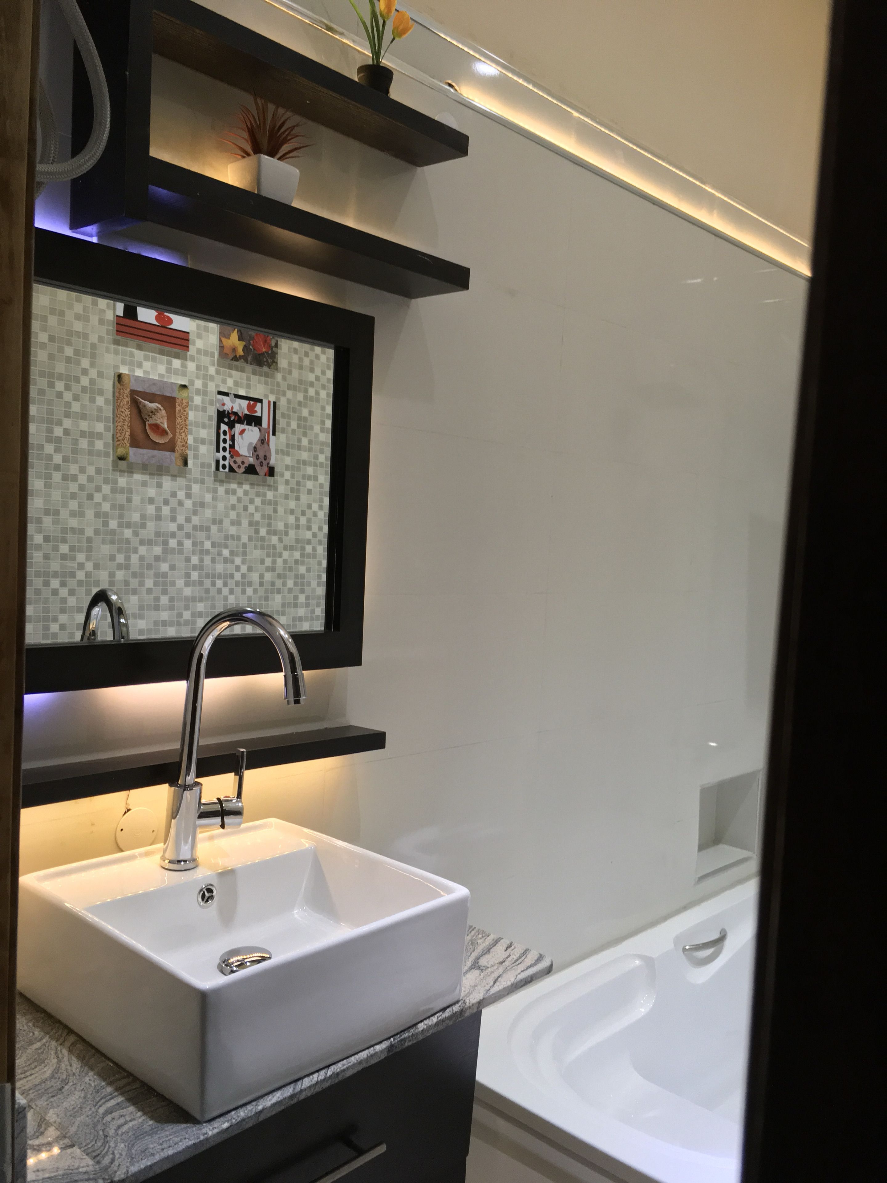 A modern bathroom with a white sink, a mirror above it, and a bathtub.