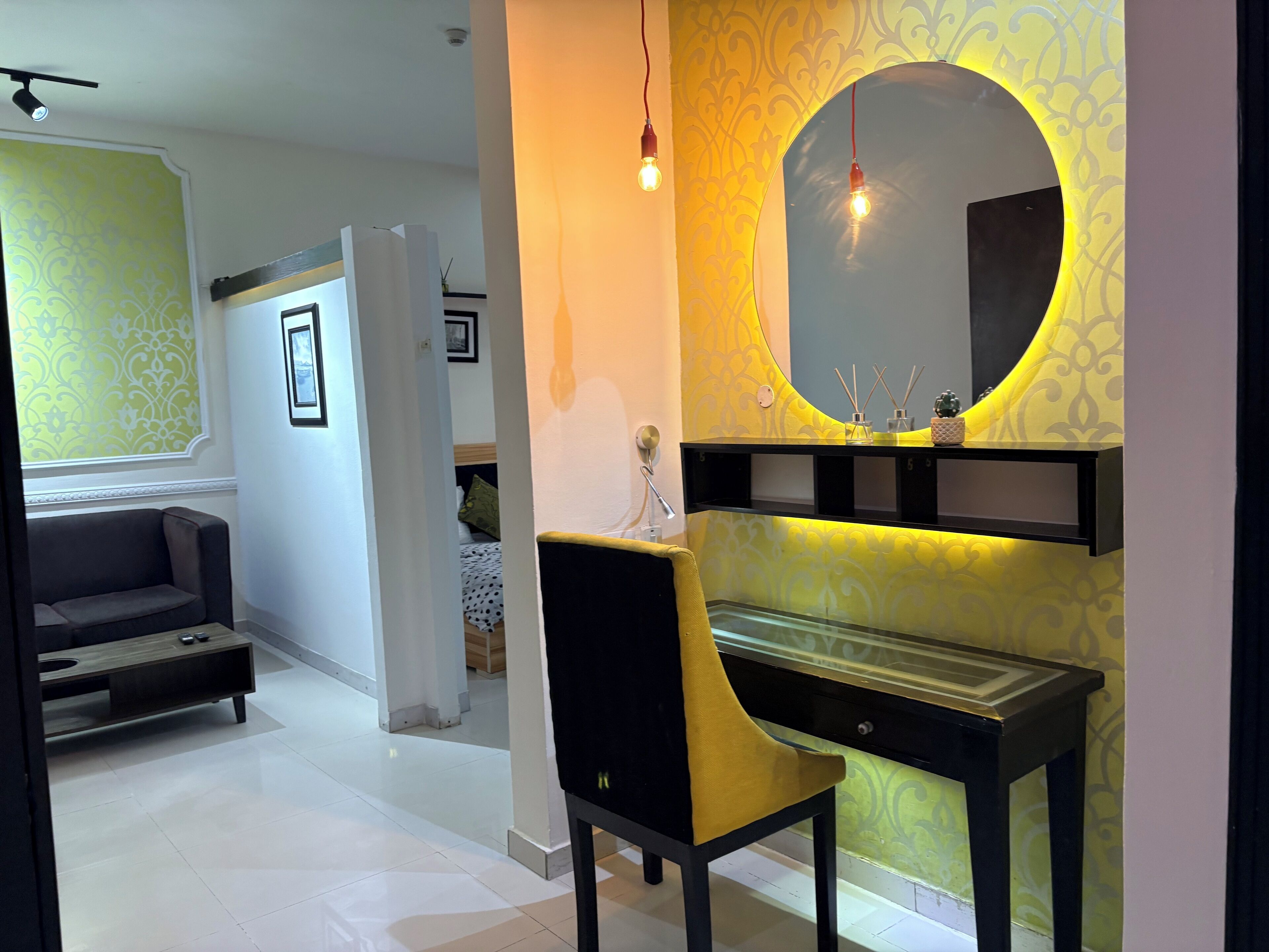 A modern living room with a sofa, a glass table, and a decorative mirror.