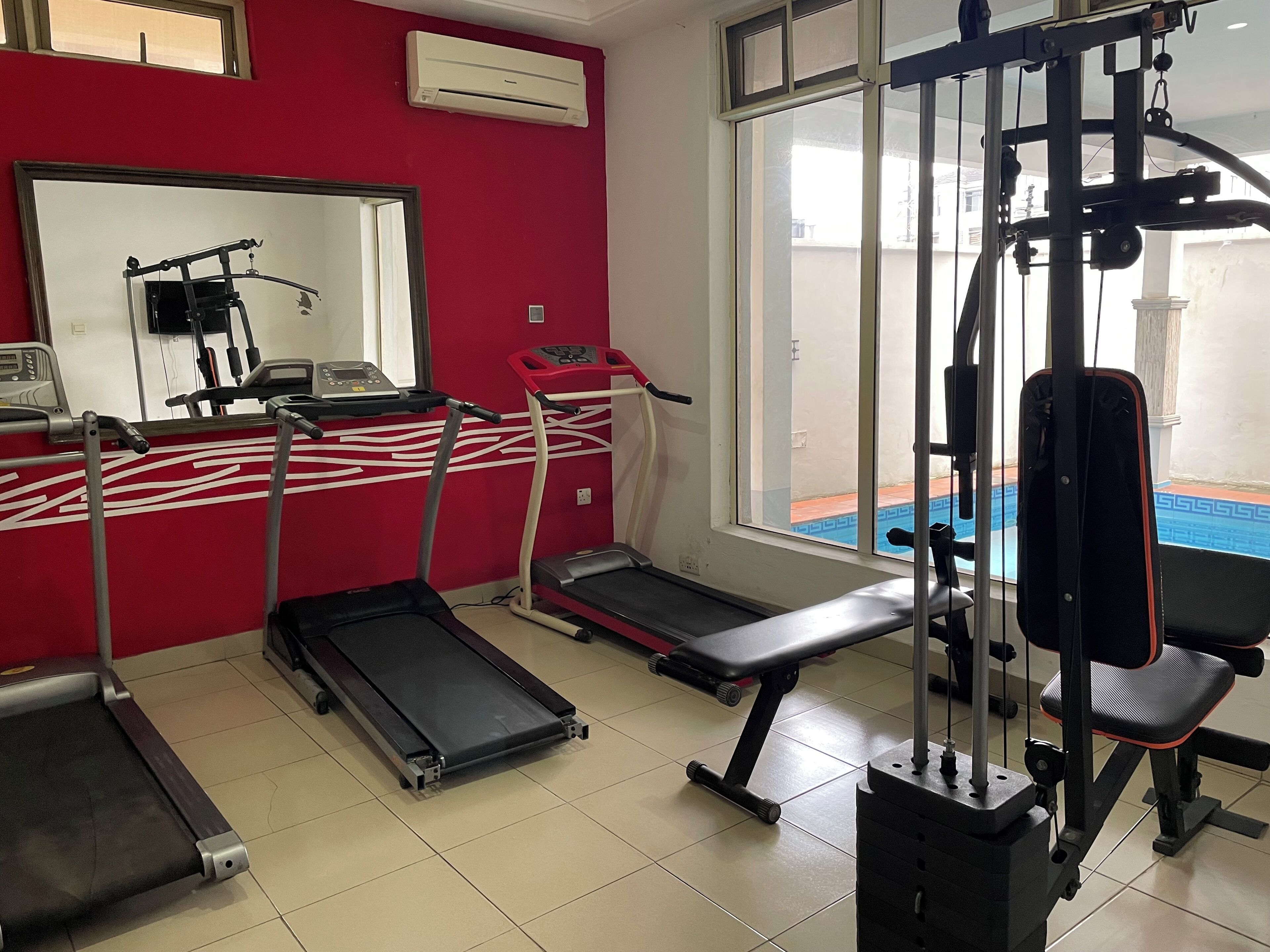 Une salle de sport équipée de tapis de course, d’un banc et d’une machine de musculation.