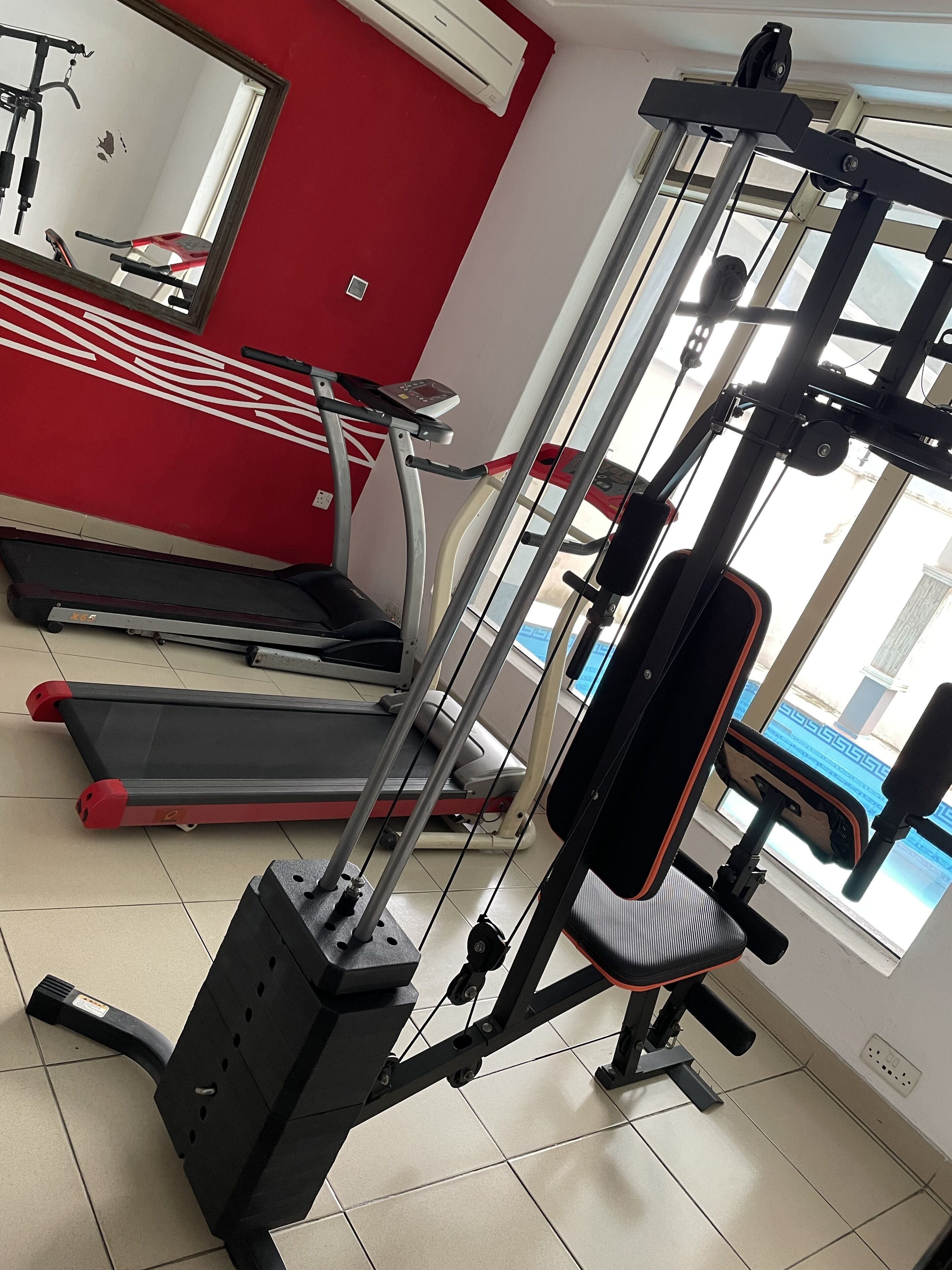 A gym with treadmills, a weight machine, and a bench.
