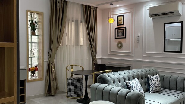Una sala de estar moderna con un sofá gris, una mesita redonda y una lámpara de pie decorativa.