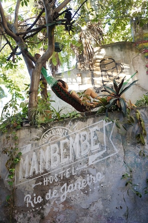 A hammock tied between trees, a chair, and a wall with graffiti.