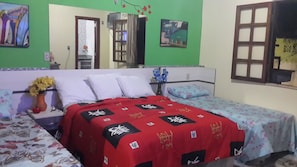 A bedroom with a bed, a nightstand, a dresser, and a window.