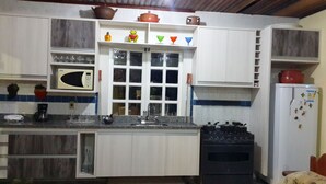 Una cocina compacta con armarios blancos, un microondas, una estufa y un refrigerador.