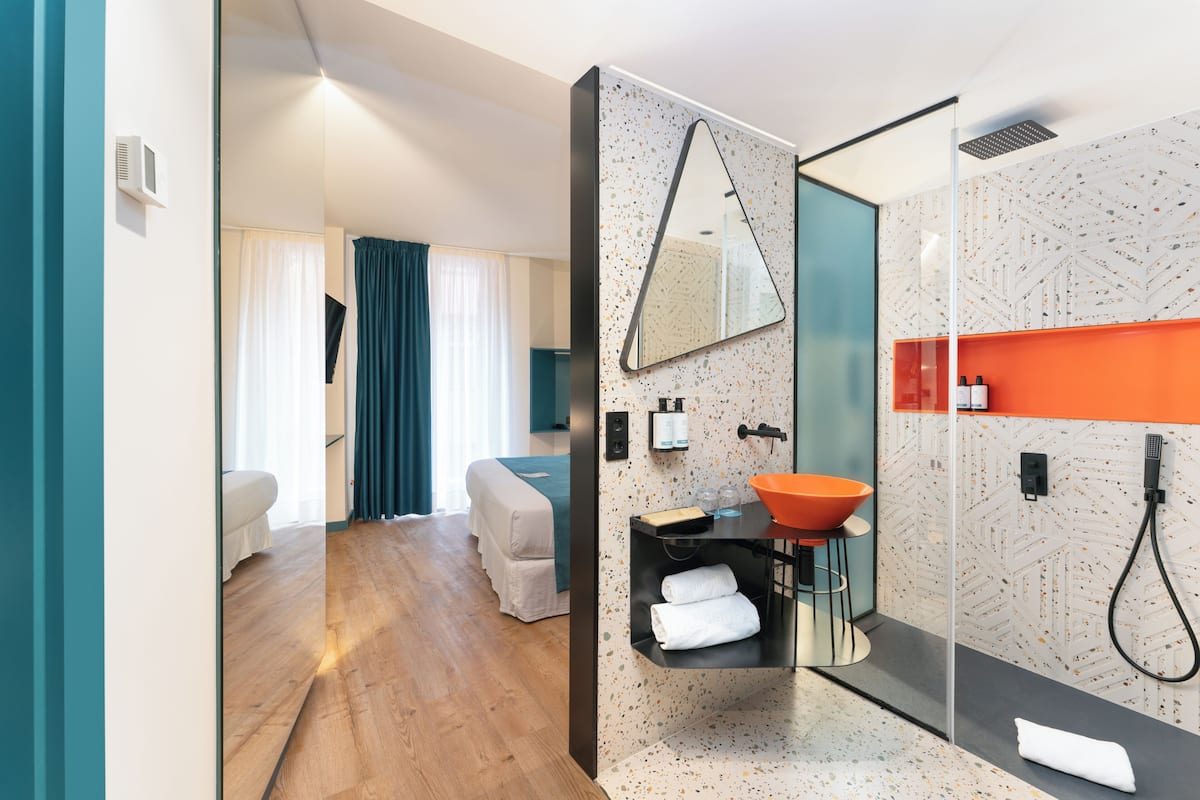 Un baño moderno con cabina de ducha de vidrio, un lavamanos independiente y un espejo grande.