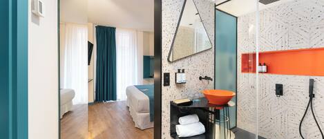 A modern bathroom with a glass shower enclosure, a freestanding sink, and a large mirror.