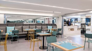 Un restaurante moderno con área de estar que incluye sofás y mesas, una barra con vitrina y un diseño limpio y contemporáneo.