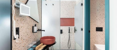 Un baño moderno con un espejo grande, un lavamanos con lavabo rojo y una zona de ducha.