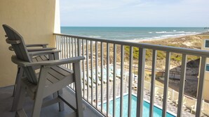 A balcony with a view of the ocean, a pool, and beach chairs. - Surf Side Hotel (Nags Head)