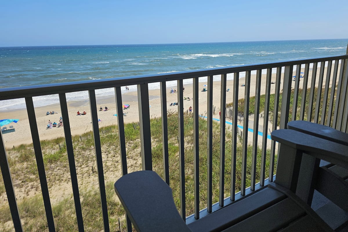 A balcony with a view of a beach and ocean.