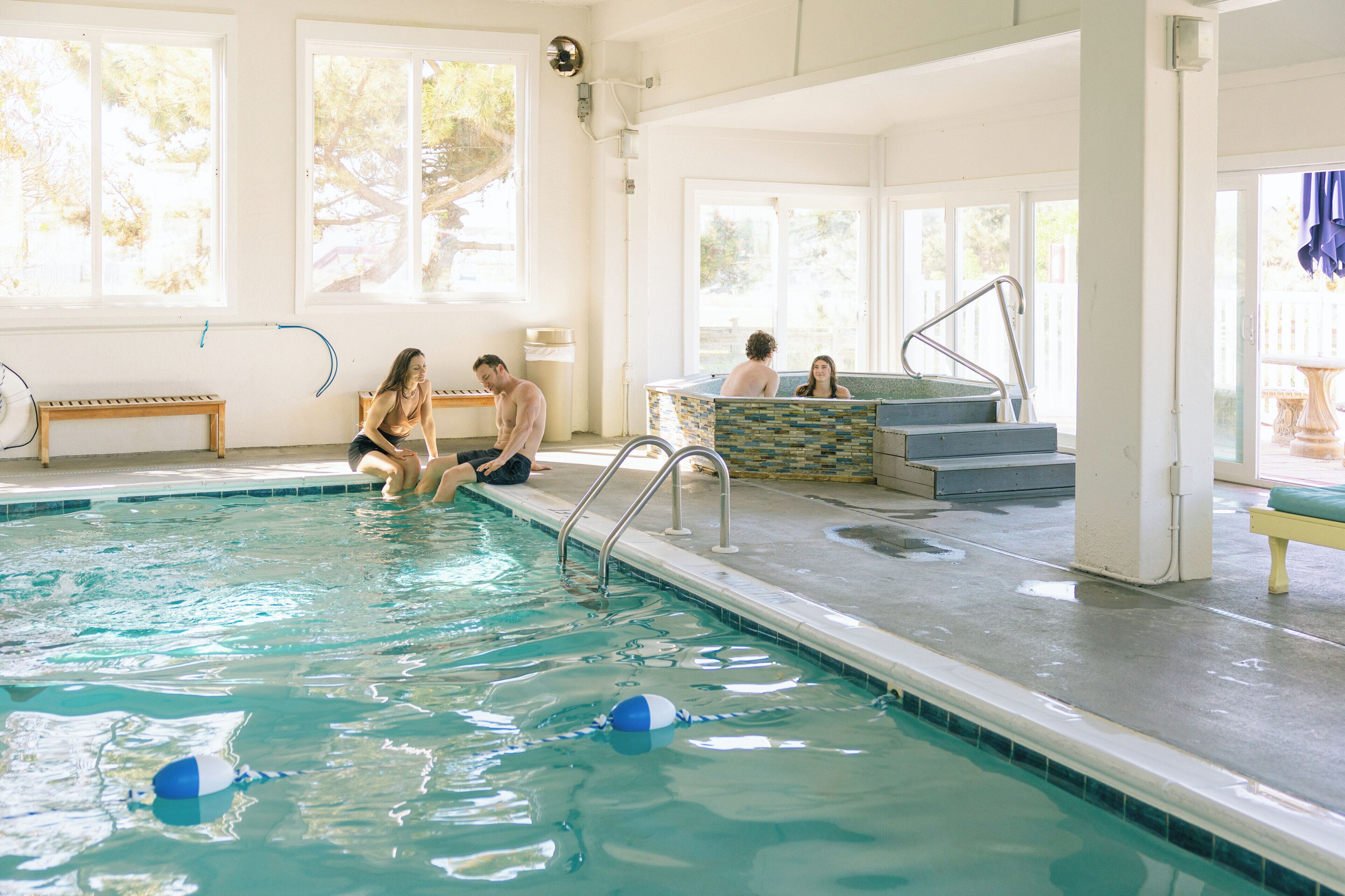 Una piscina interna con acqua cristallina, un trampolino e scalini per entrare.
