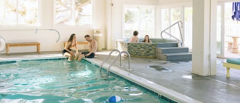Una piscina interna con acqua cristallina, un trampolino e scalini per entrare.