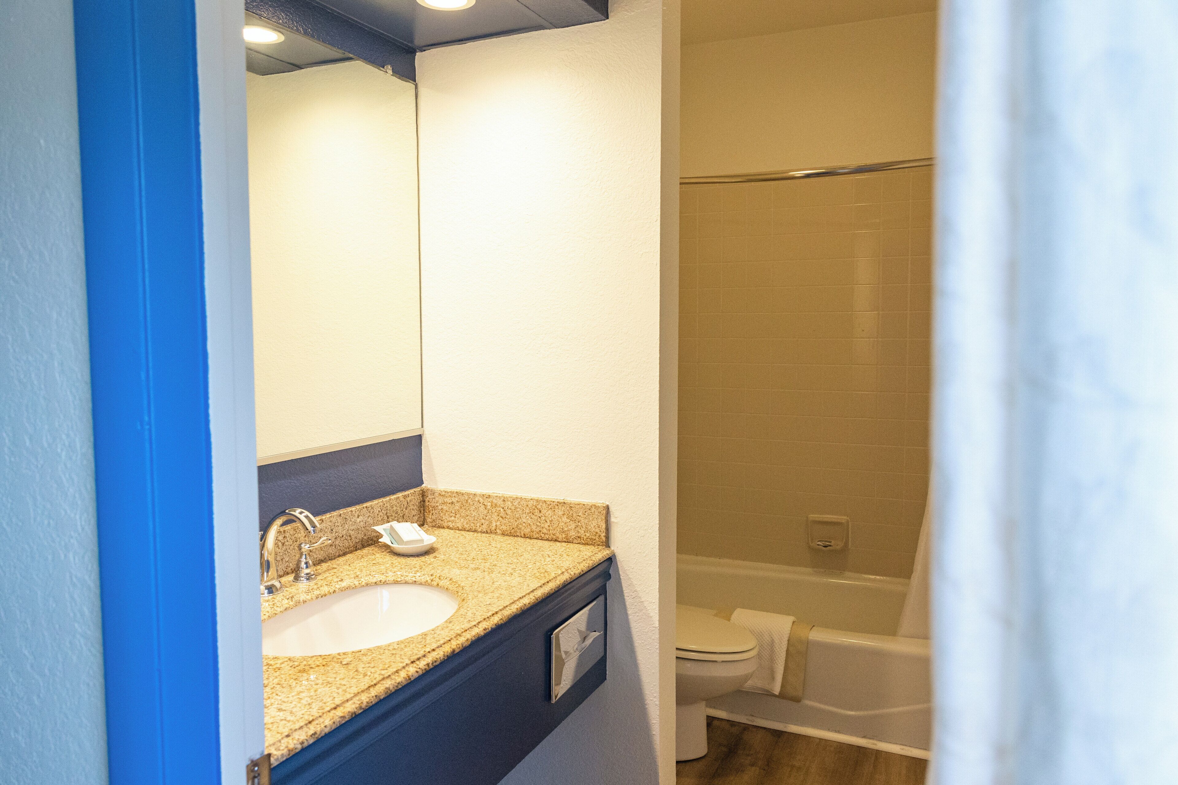 A bathroom with a sink, mirror, and bathtub.