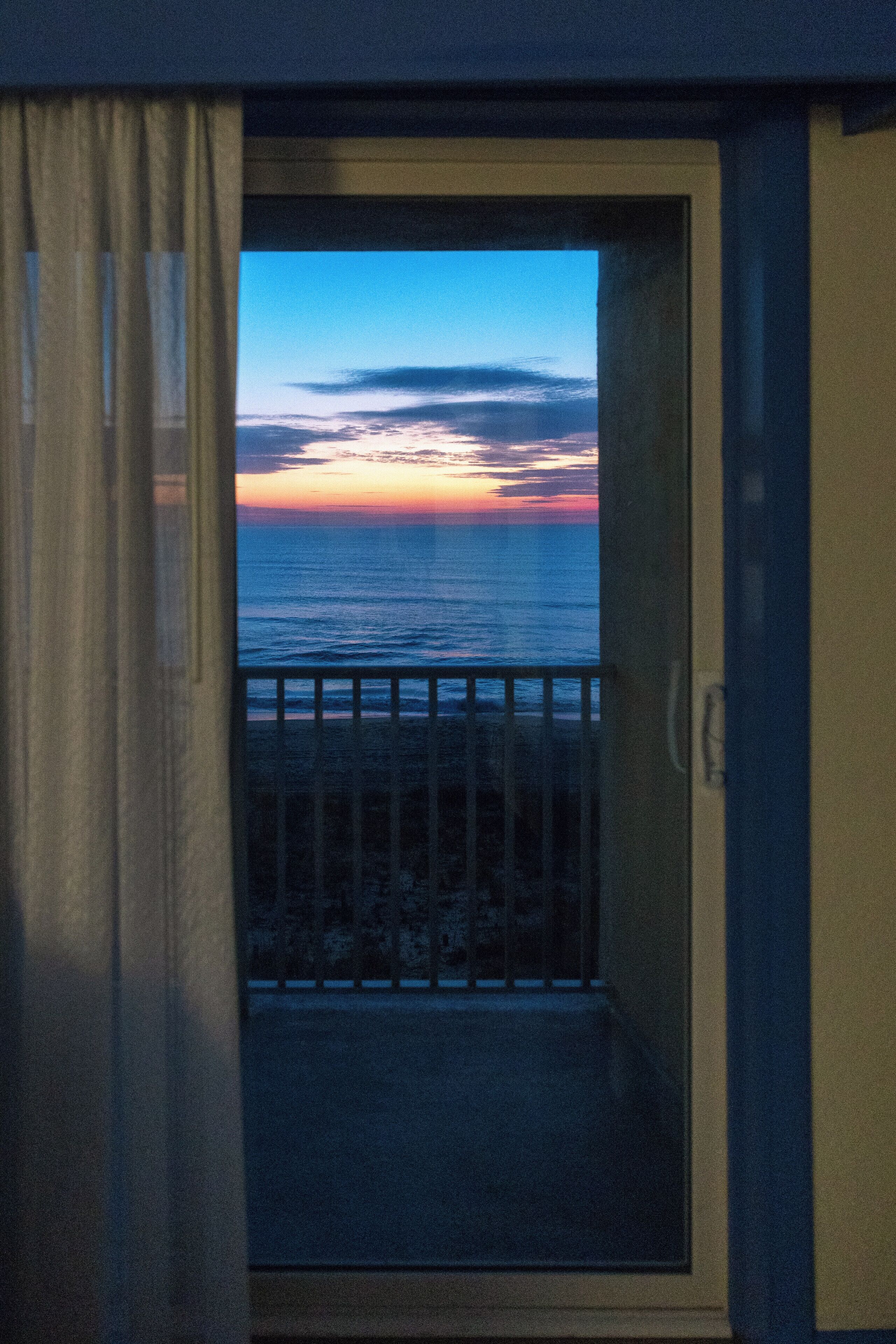 Un balcon avec vue sur l’océan au coucher du soleil.