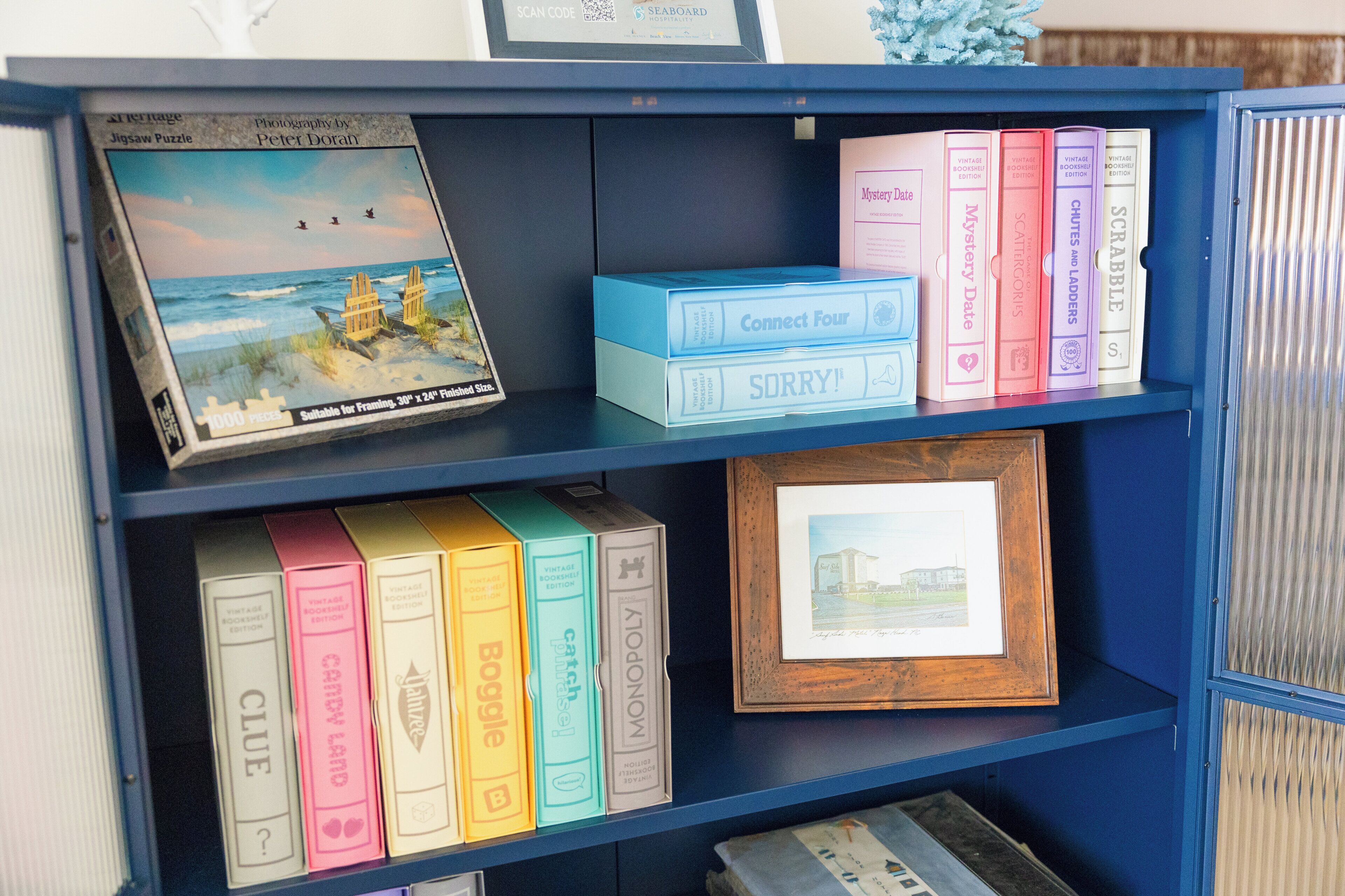 A bookshelf with various board games and a framed picture.