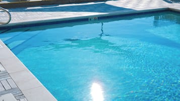 Alberca techada, alberca al aire libre y sombrillas en la alberca