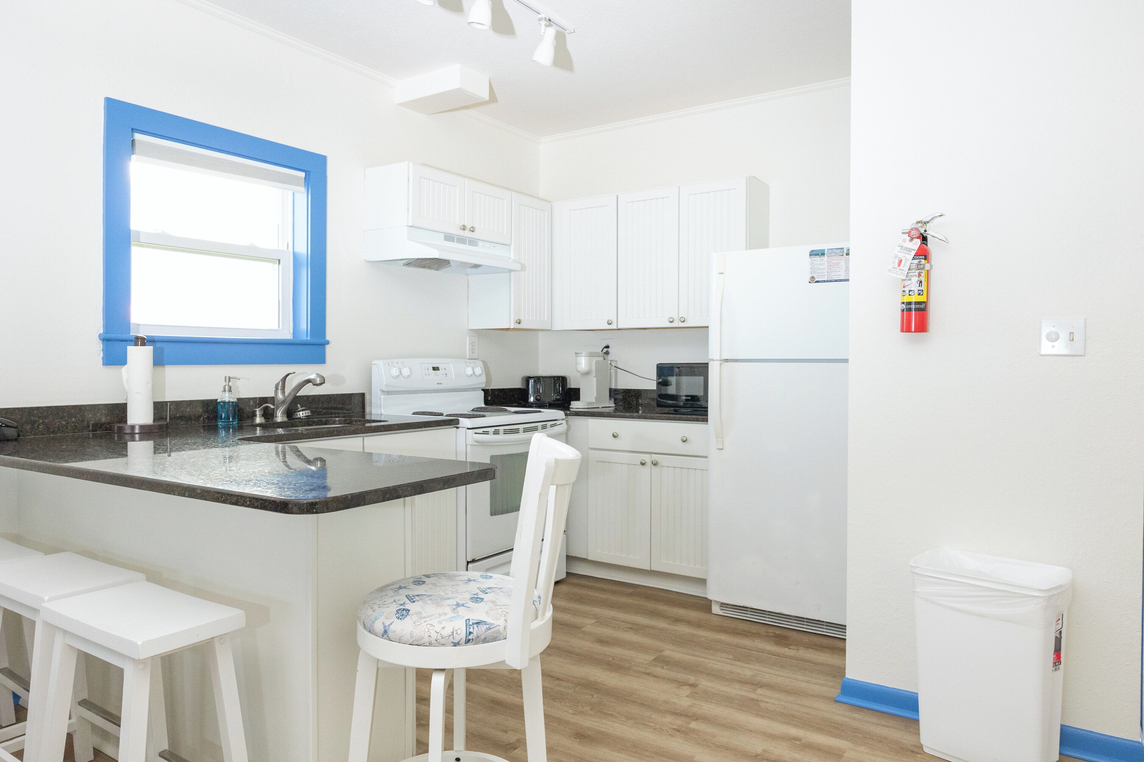 A modern kitchen with white cabinets, a built-in stove, and a refrigerator.