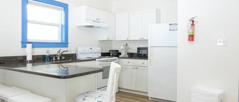 A modern kitchen with white cabinets, a built-in stove, and a refrigerator.