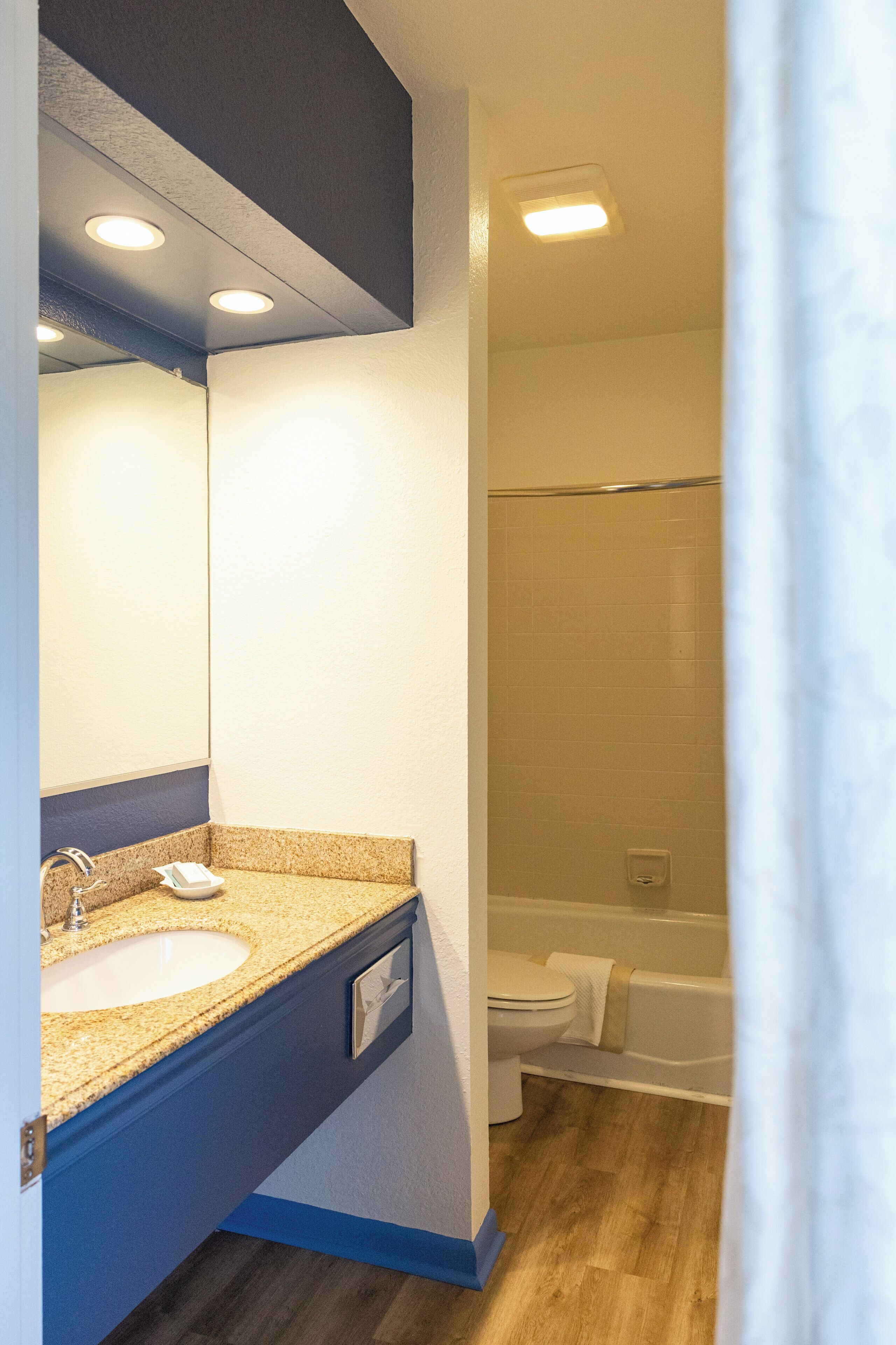 A bathroom with a sink, mirror, and shower area.