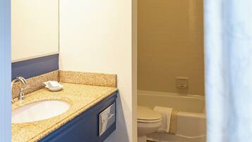 A bathroom with a sink, mirror, and shower area.