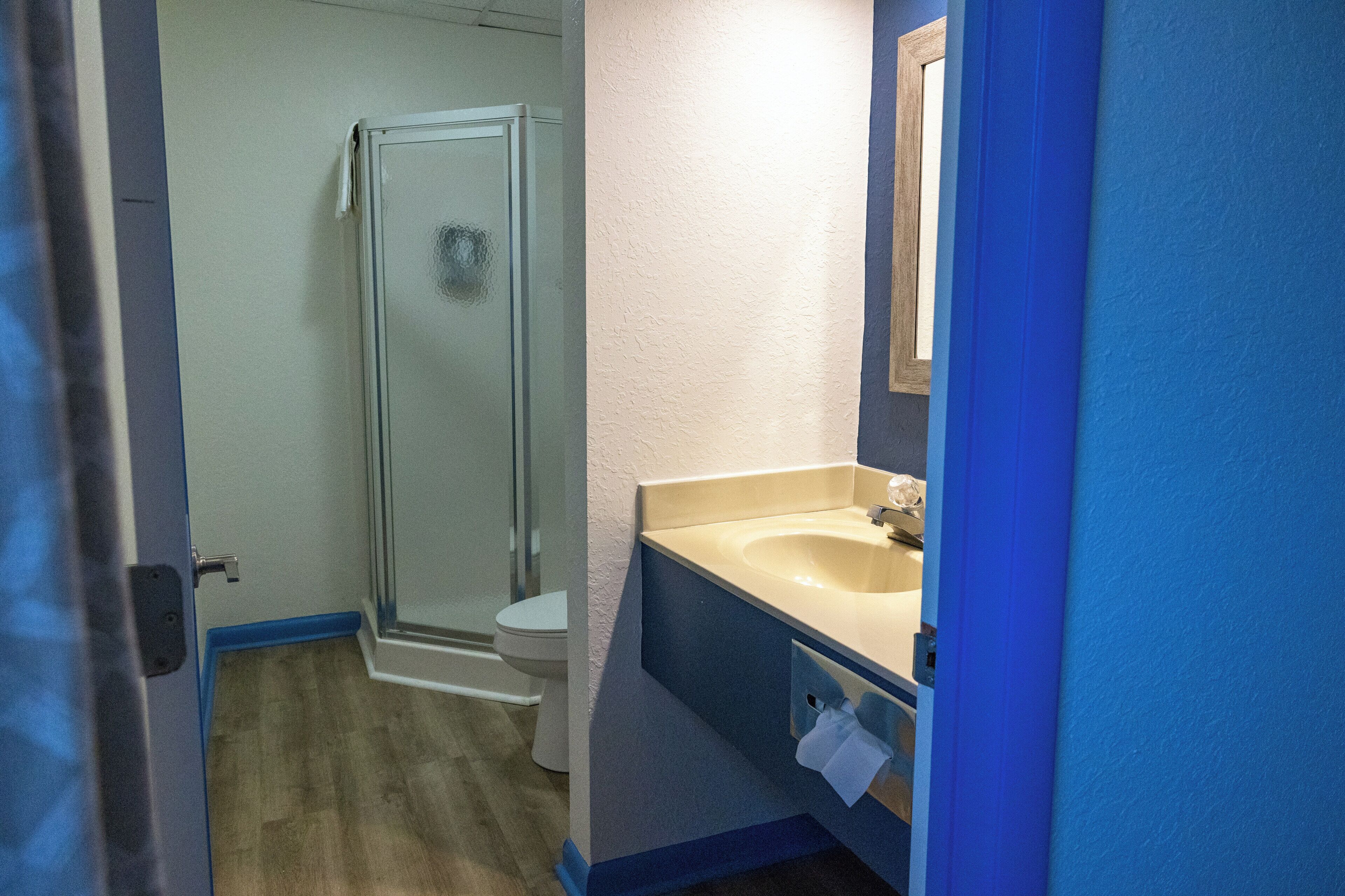 Un bagno con cabina doccia in vetro, un water bianco e un lavandino con specchio.
