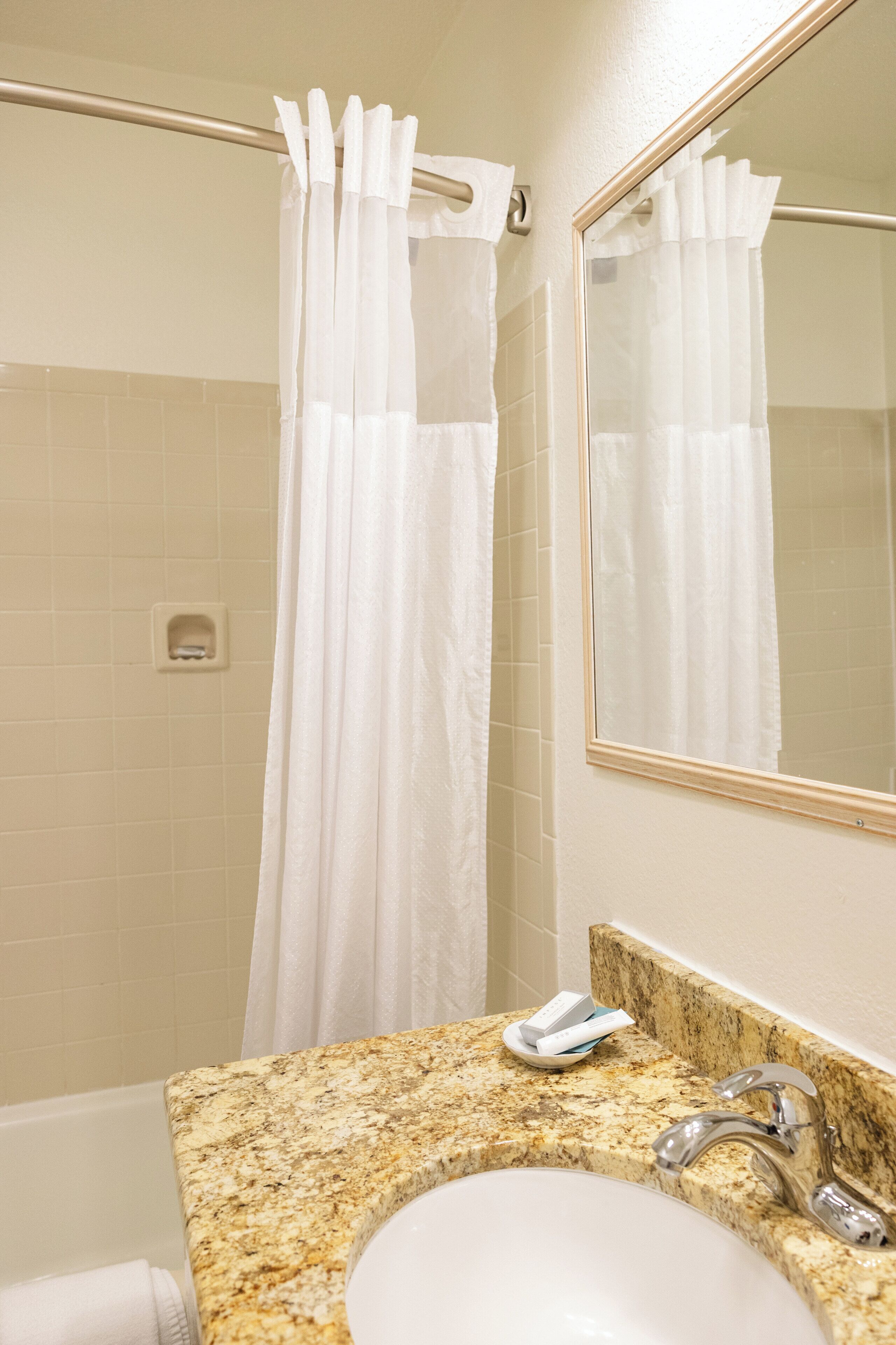 Une salle de bain avec un lavabo, un miroir et un rideau de douche.