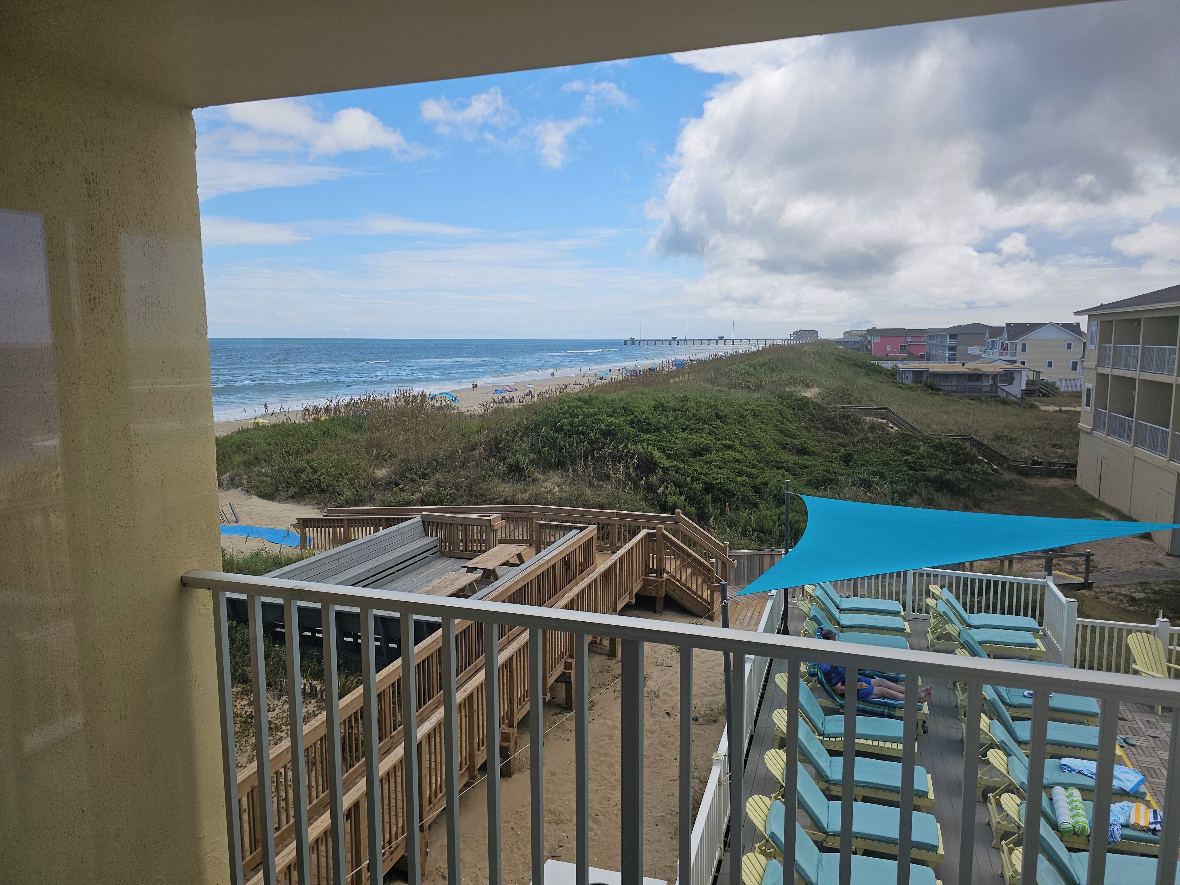 Ein Balkon mit Blick auf den Strand, mit Holzboden und Liegestühlen.