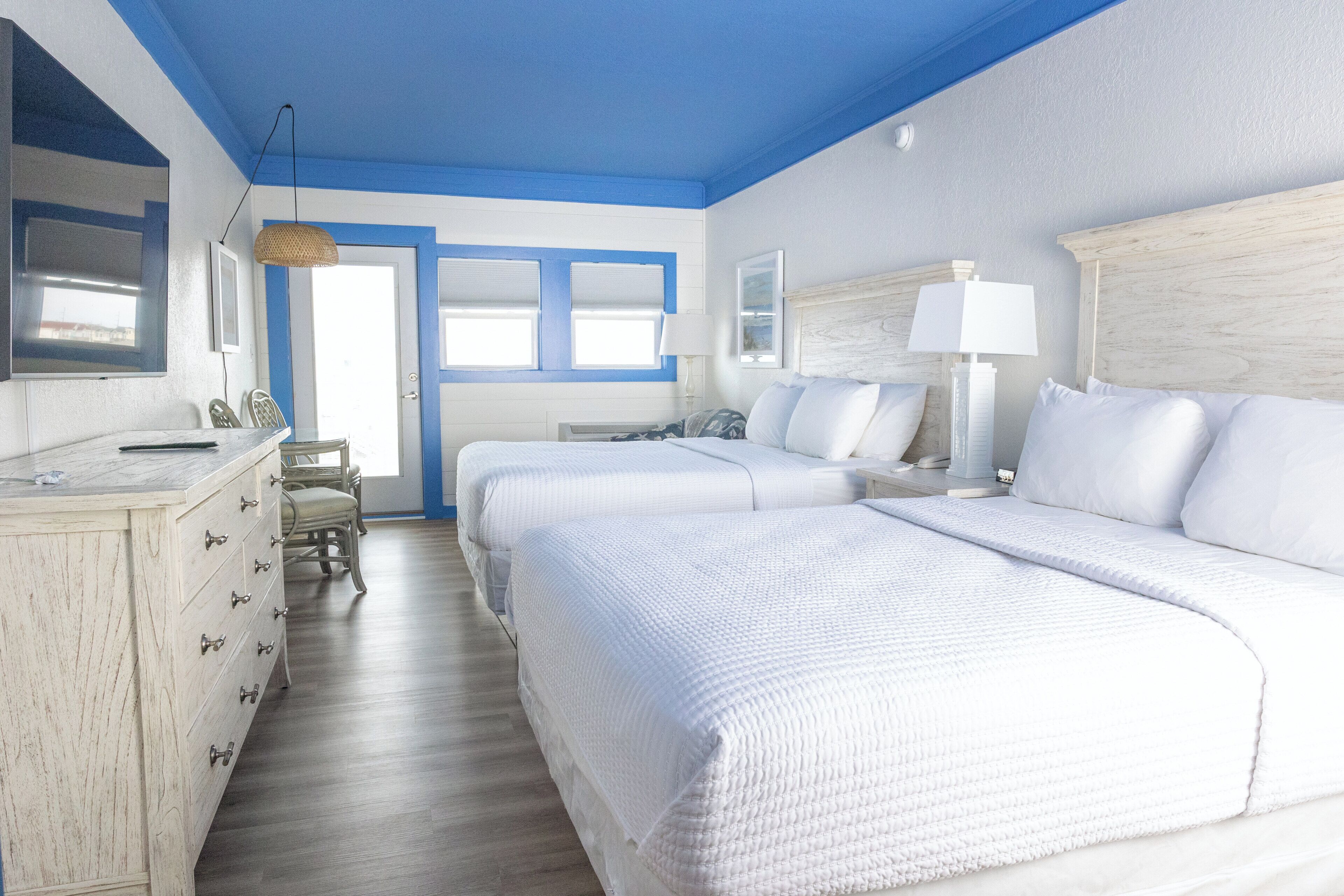 A hotel room with two beds, a dresser, a desk, and a chair.