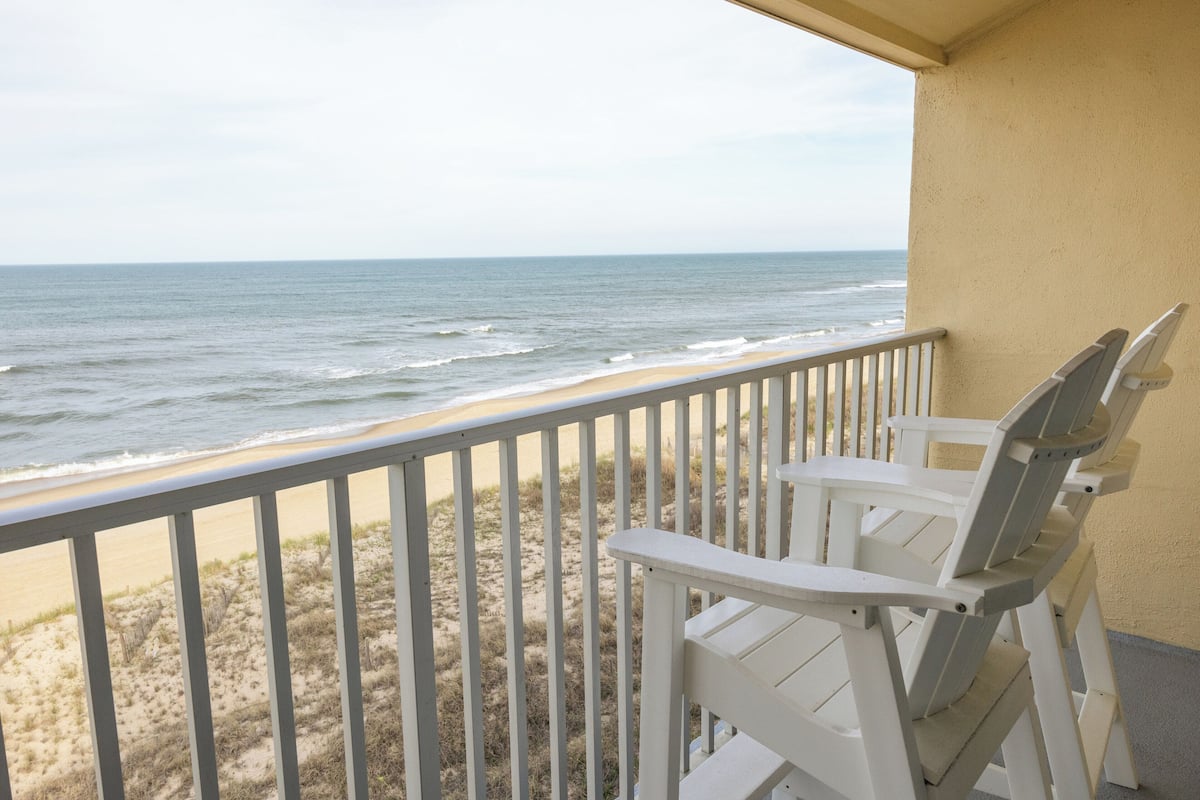 A balcony with a view of the beach and ocean.