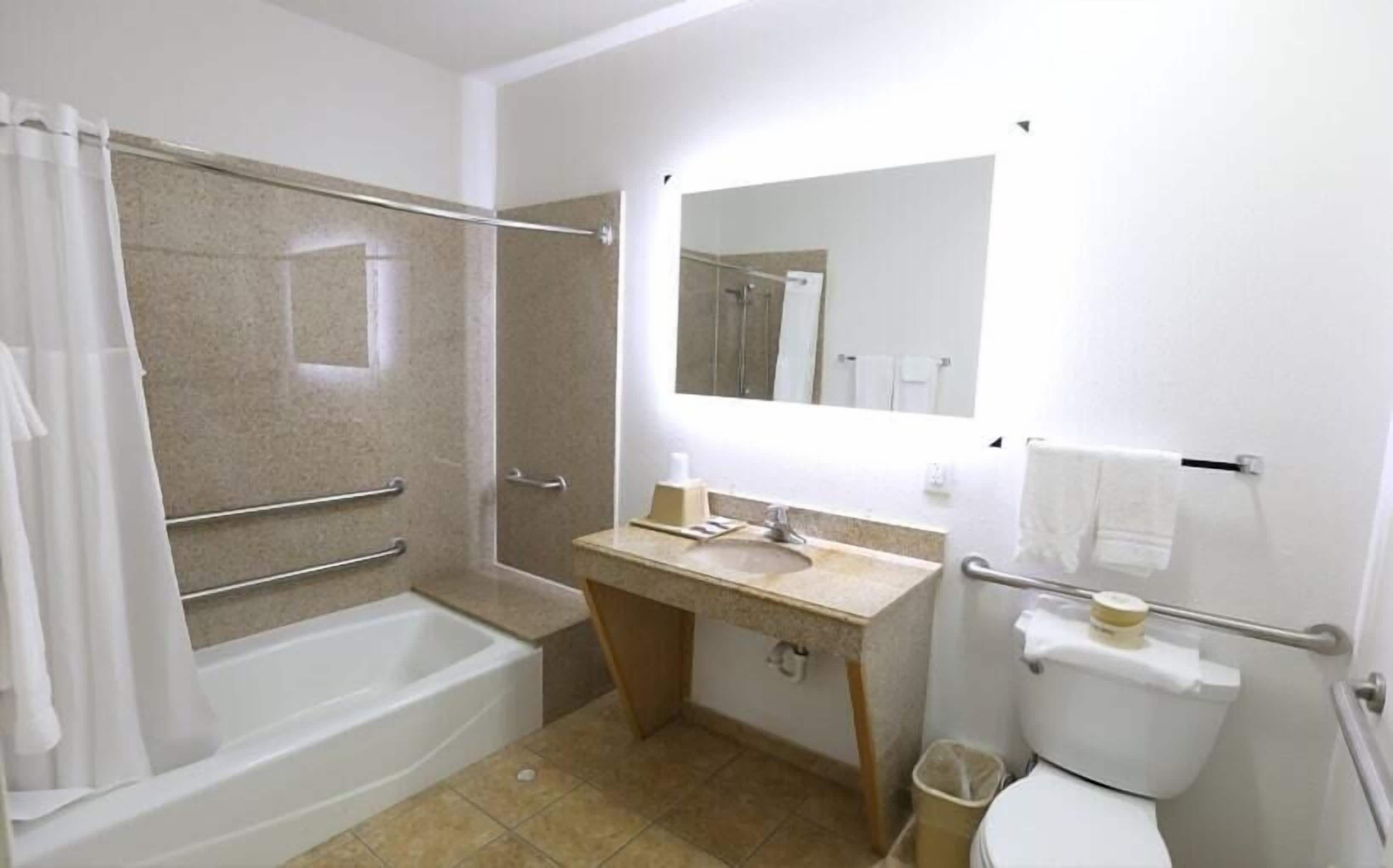 A bathroom with a bathtub, a sink, a toilet, and a shower area.