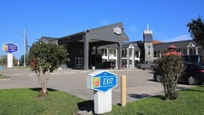 Una estación de servicio con un letrero de 'EXIT', una iglesia y algunos coches estacionados al frente.