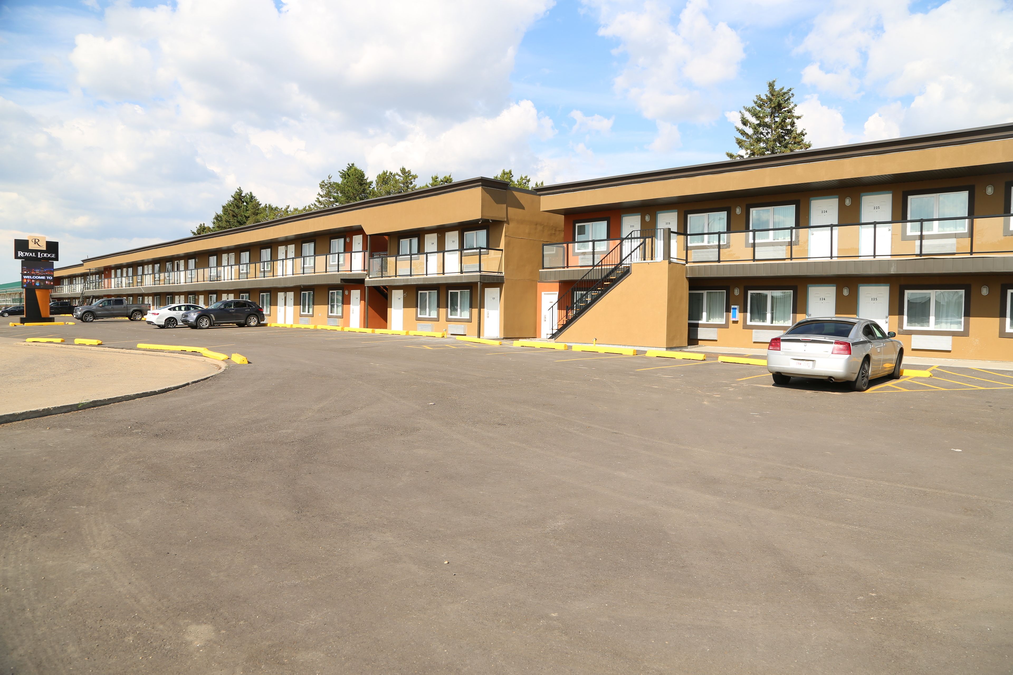 Un motel con diversi piani, un parcheggio e cielo sereno.