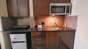 A compact kitchen with a microwave, refrigerator, and a coffee maker. - Royal Lodge (Edmonton)