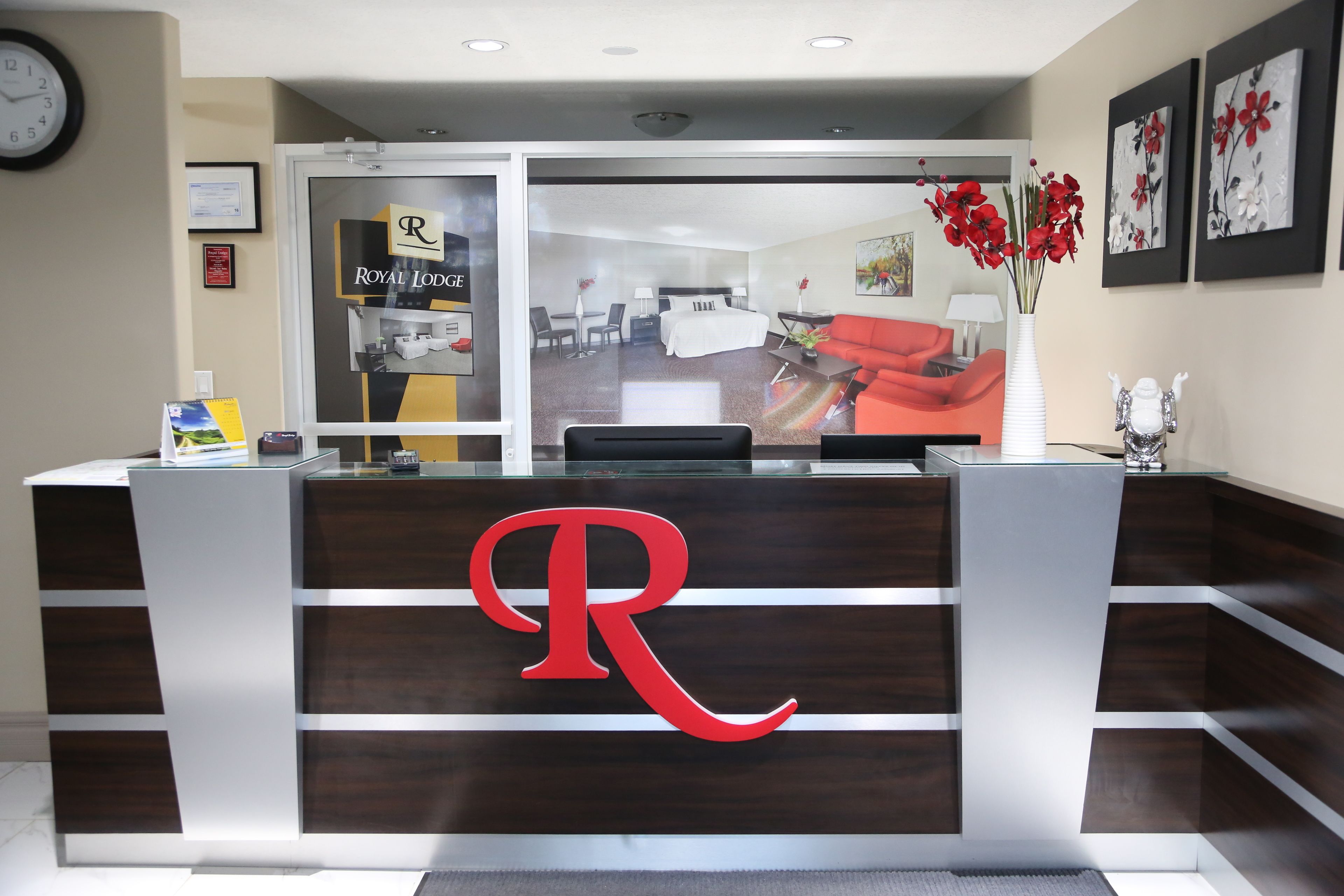 Un comptoir d’accueil orné d’un grand logo en forme de « R », une horloge au mur et des certificats encadrés.