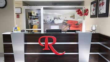 Un comptoir d’accueil orné d’un grand logo en forme de « R », une horloge au mur et des certificats encadrés.